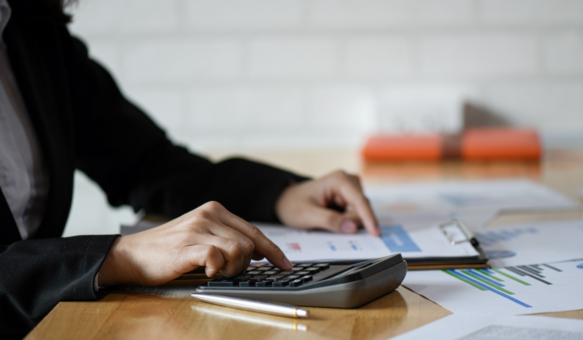 Woman calculating a budget with a calculator.