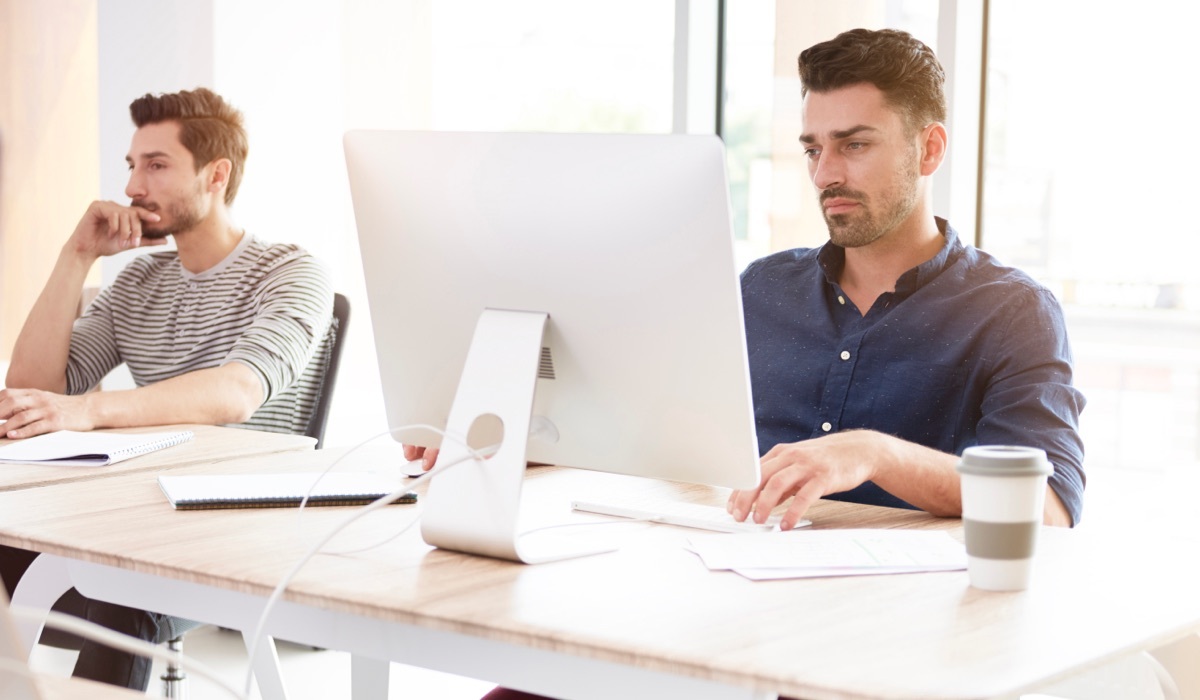 Two men working at their computers in an open office.