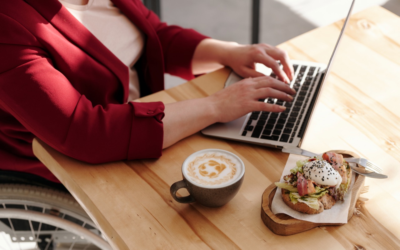 A woman working at the computer with her lunch on the table