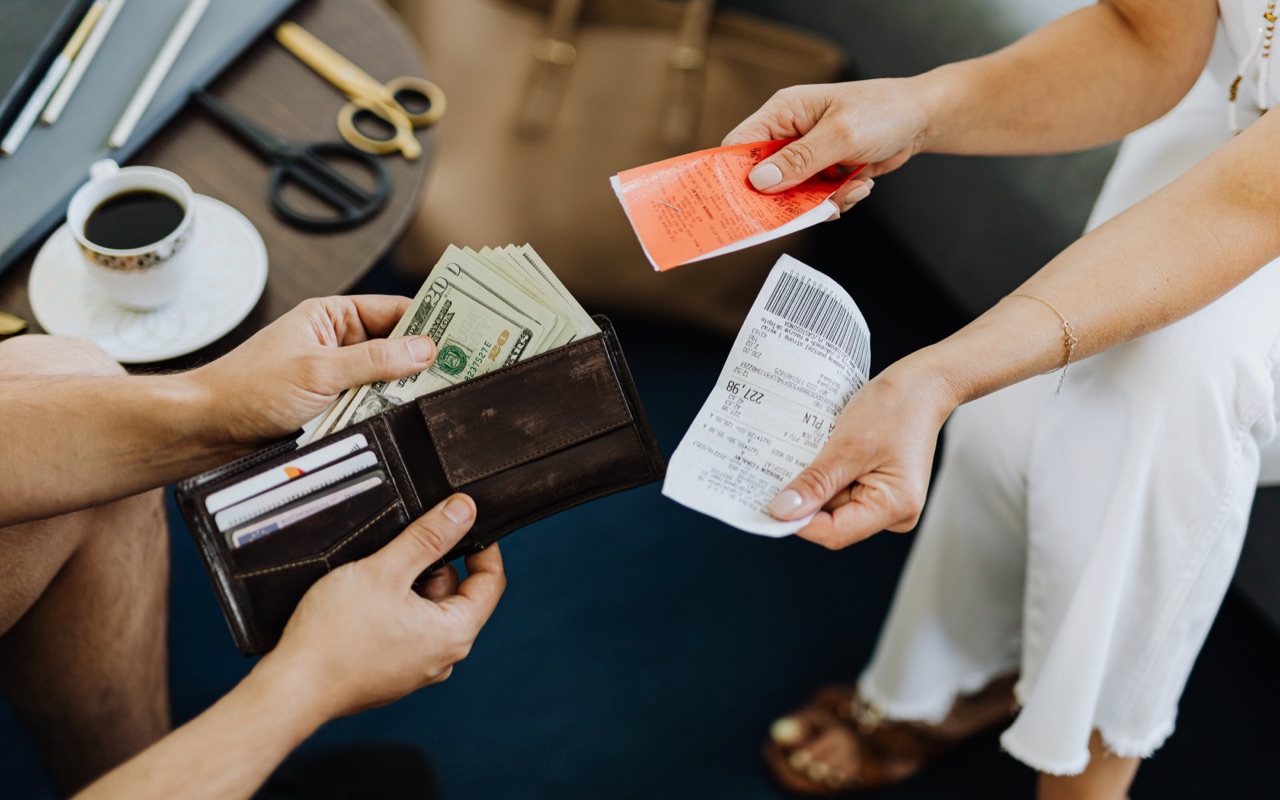 A woman handing a receipt to a man giving her cash in payment