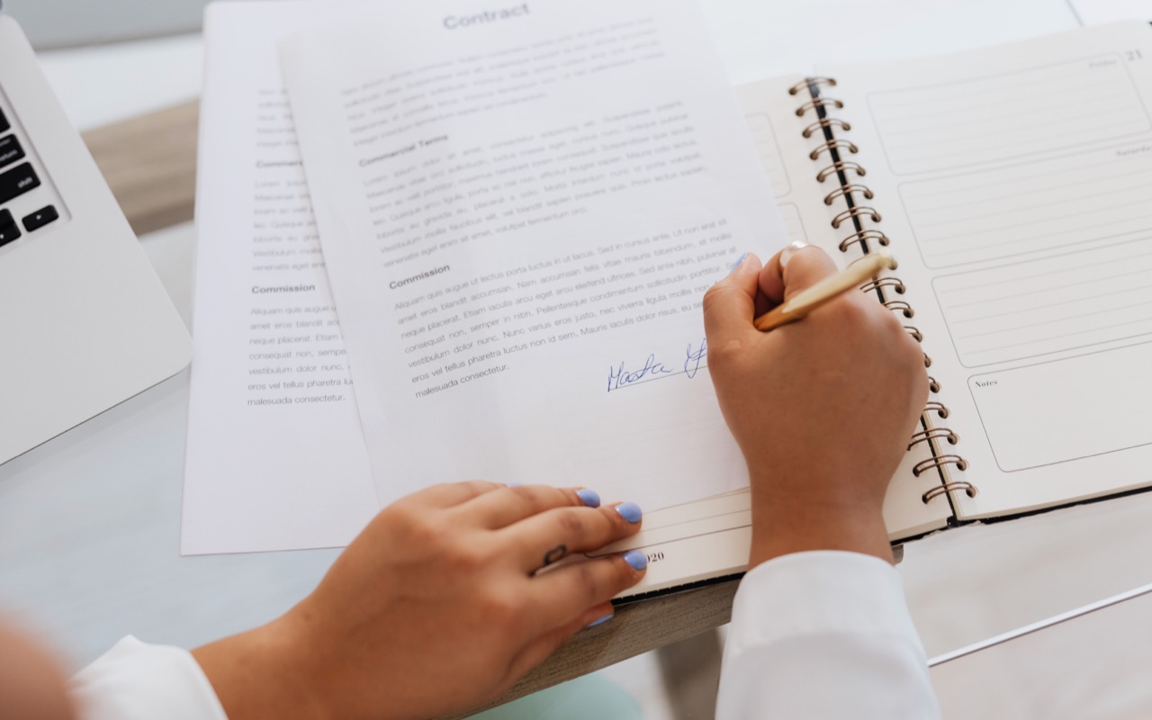 A woman signing a contract including a travel expense policy