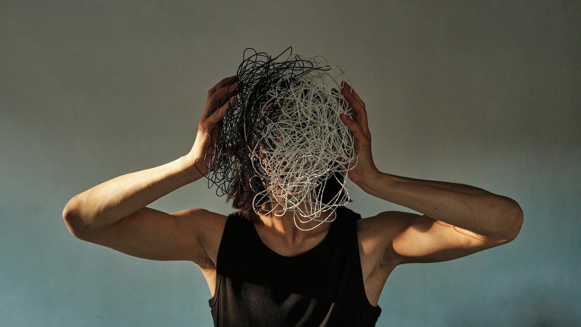 A man holding a mess of wires in front of his head