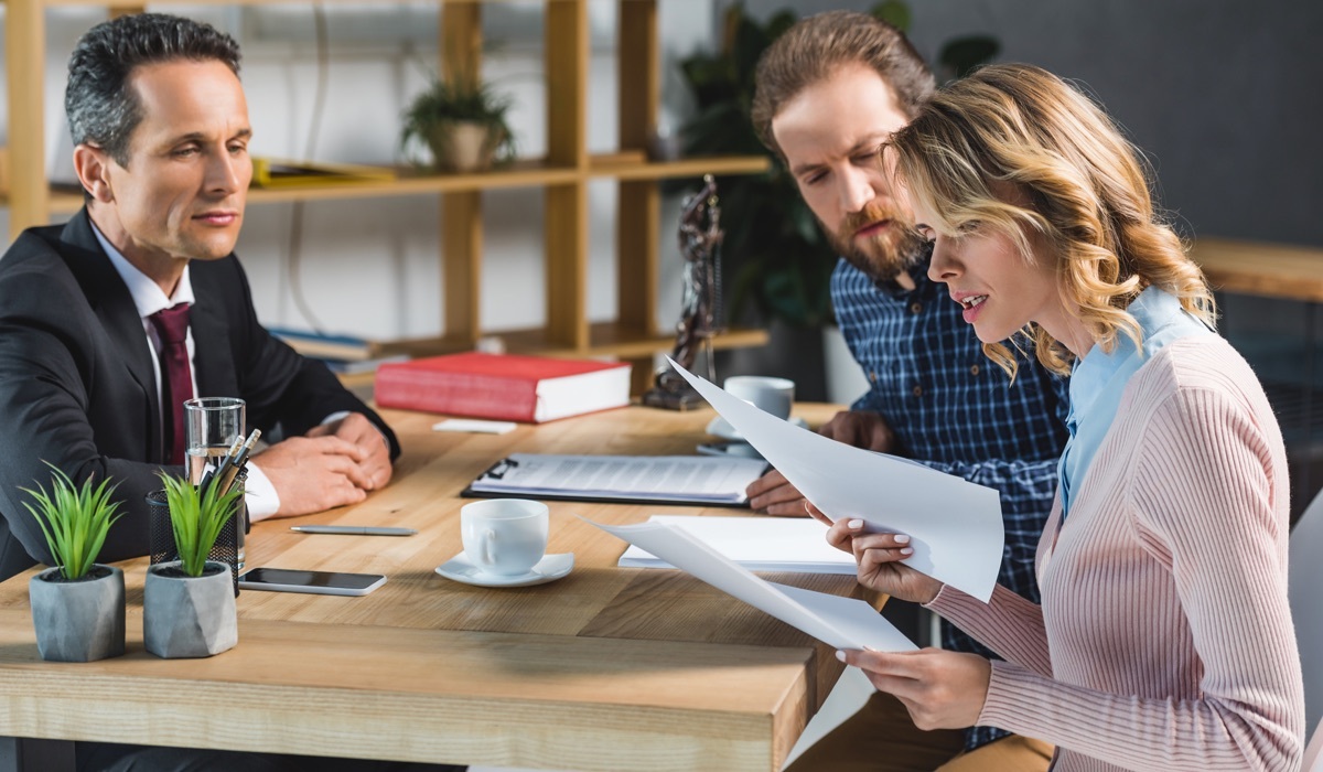 A couple reading the retainer agreement at a meeting with a lawyer.