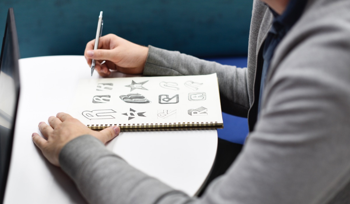 A designer sketching logos on a sketch book.