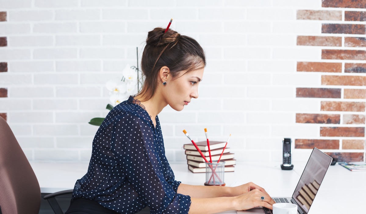 Woman at her computer, emailing a design brief to a designer.